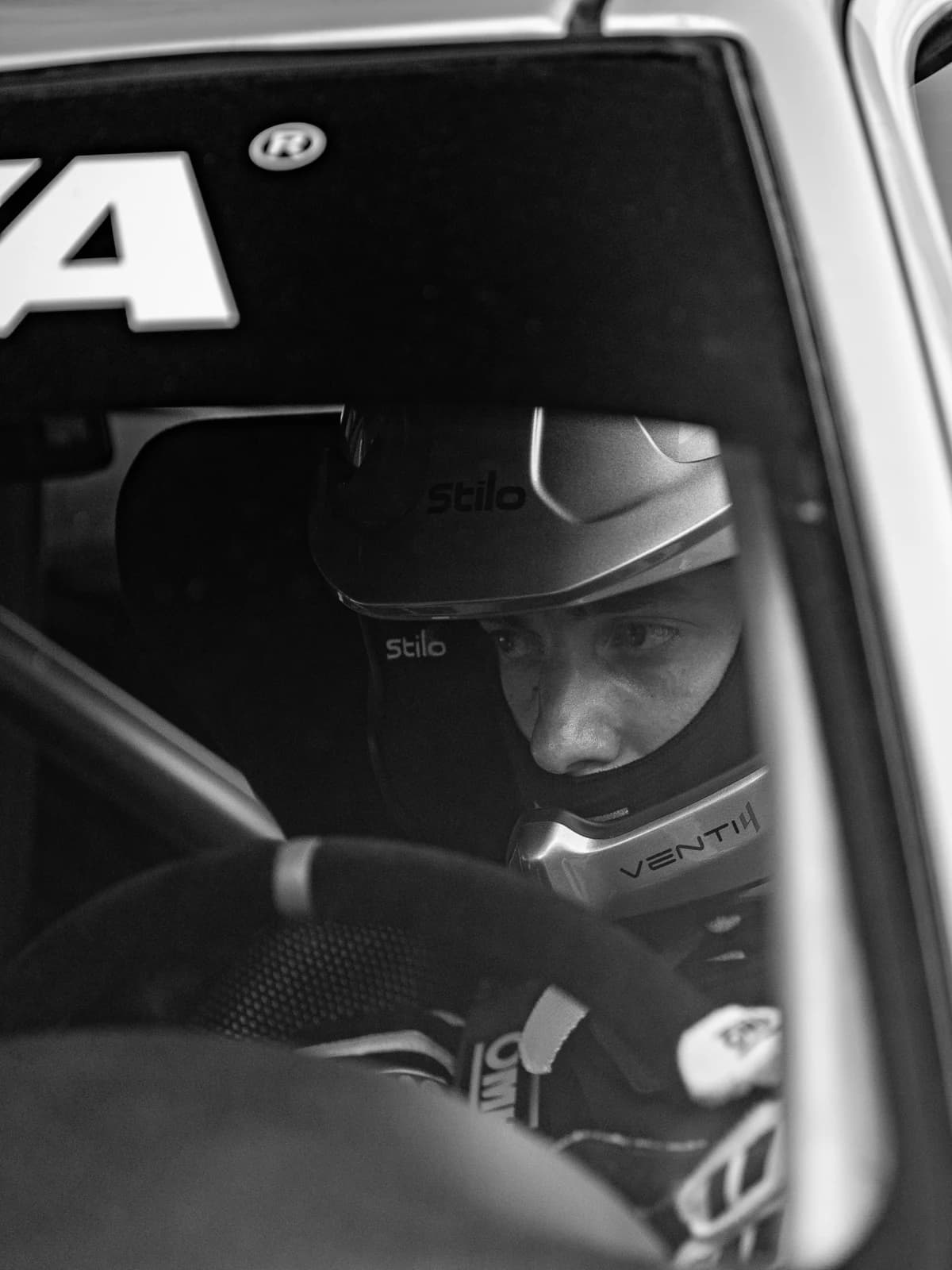 Adrián González dentro del coche con casco Stilo, mirada concentrada antes del tramo, blanco y negro
